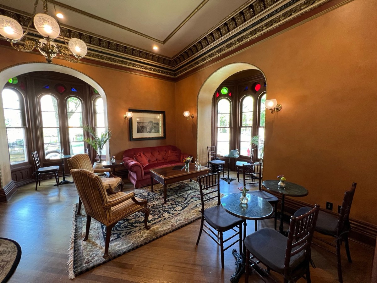 The parlor at the Mansion Hill Inn, with arched stained-glass windows, a red velvet sofa and a gas chandelier