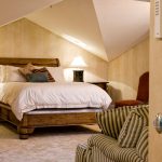 Vaulted ceilings encompass this king-sized dormitory with lighted lamps flanking the bed.