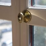 A brass doorknob on windowed doors leading outside.