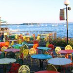 A sunny view of Lake Mendota behind the Memorial Terrace filled with the colorful and iconic "Terrace Chairs".