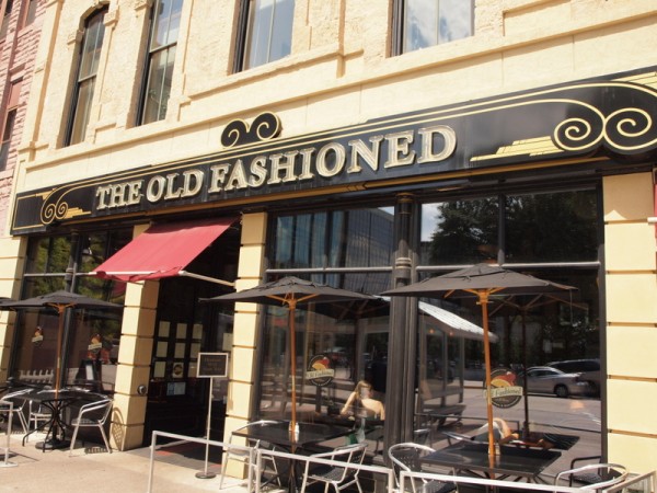 An exterior view of the outside of The Old Fashioned with dining tables on the sidewalk.